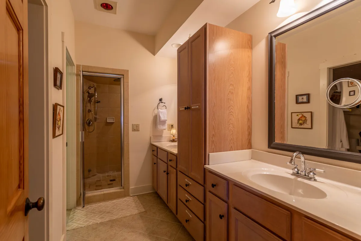 A modern bathroom with a double sink vanity, large mirror, ample lighting, and a spacious walk-in shower. The clean, organized design suggests a space for both practicality and restful routines.