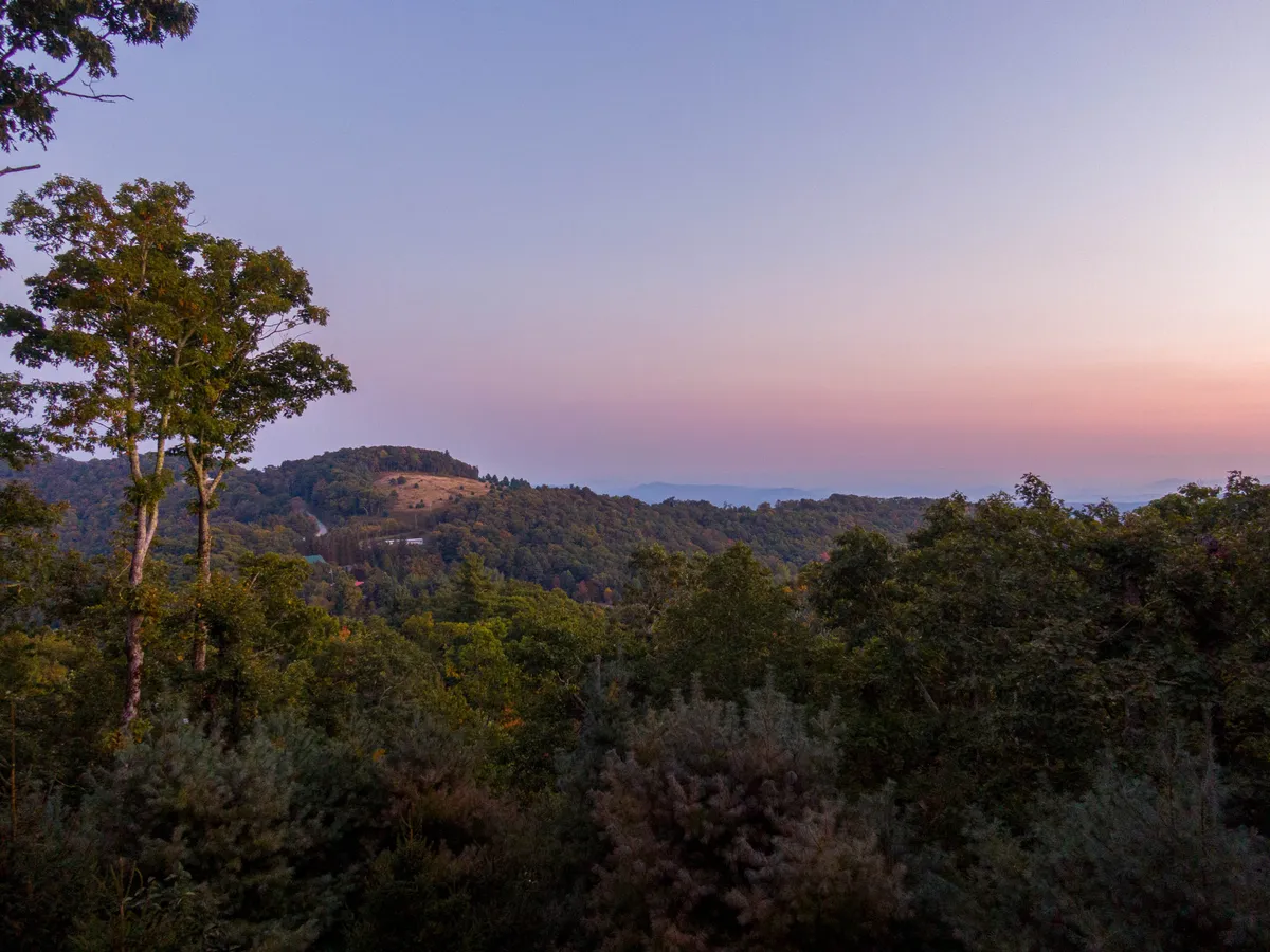 A breathtaking view of the mountain range with a natural tree line and a softly colored sky, capturing the serene beauty of the area’s hiking opportunities.